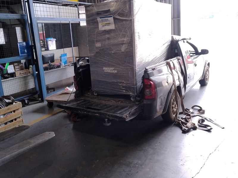 Picape carregada saindo de um galpão industrial